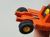 a hand holding a toy tractor with a yellow wheel