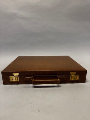 valise en cuir marron avec des poignées en laiton sur fond blanc