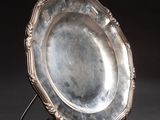 an antique silver plate on a stand against a black background