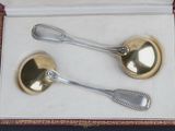 two silver spoons in a box on a table