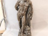 statue représentant un homme assis sur un rocher, tenant un chien dans ses bras