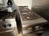 deux cuisinières dans une cuisine, surmontées d'un ventilateur