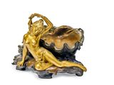 a gold statue of a woman laying on a shell