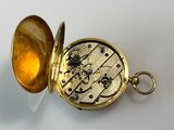 a gold colored pocket watch with a gold colored case