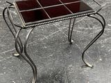 a small metal table with a glass top on a concrete floor