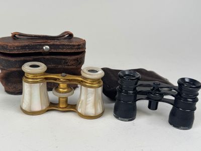 two pairs of binoculars and a case on a white surface