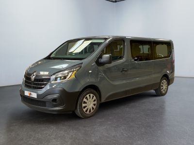 La camionnette grise est garée dans une grande pièce au sol noir.