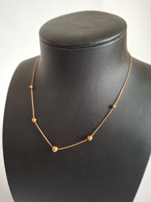 a black mannequin with a gold chain and beads on it