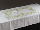 une table recouverte d'une nappe blanche ornée de fleurs jaunes