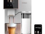 a white coffee machine with a cup of coffee next to it
