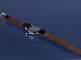 wrist watch with brown leather strap on a blue surface