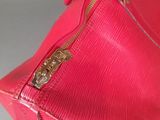a close up of a pink purse on a white surface