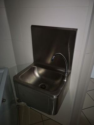 un lavabo en acier inoxydable avec un robinet, situé dans un coin de la salle de bains