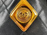 a close up of a chanel bag with a gold button on it