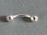 a silver ring with two balls on it on a gray surface