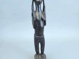 une petite statue représentant une femme tenant sa tête entre ses mains