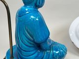 a blue buddha statue sitting on top of a table next to a plate of food
