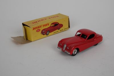 une petite voiture rouge posée à côté d'une boîte sur une surface blanche