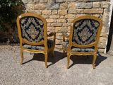 two chairs sitting next to each other in front of a stone wall