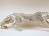 une figurine en argent représentant un guépard en pleine course sur un fond blanc