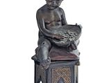 statue of a boy sitting on a stool holding a bowl of fruit