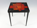a small table with a red and black mosaic design on it