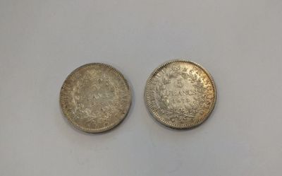two silver coins sitting next to each other on a white surface