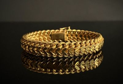 gros plan d'un bracelet en or sur une surface noire