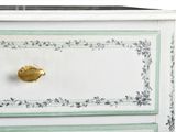 a white dresser with a gold knob on top of it