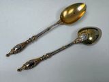 two spoons are sitting side by side on a white surface