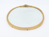 a round mirror on a white surface with a gold frame
