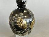 a black and gold vase sitting on a white surface