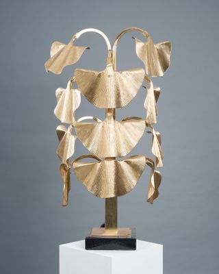 an image of a gold sculpture of leaves on a white pedestal