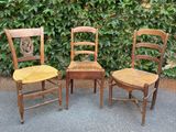 trois chaises en bois placées les unes à côté des autres devant une haie