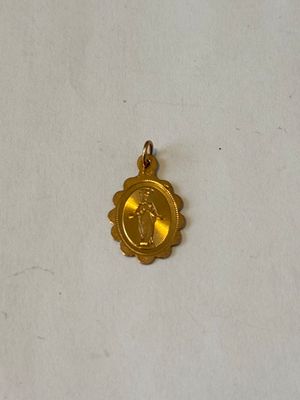 un gros plan d'une petite médaille d'or posée sur une surface blanche