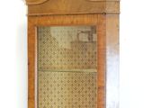a wooden cabinet with a glass door on the wall