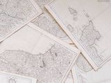 many maps of the world on a table with a cup of coffee