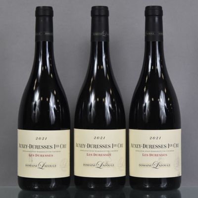 three bottles of red wine sit on a glass table