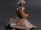 statue of a woman sitting on a turtle on a black background