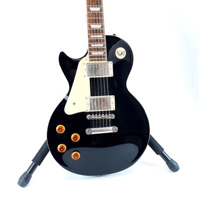 a black electric guitar sitting on a stand on a white surface