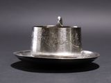 a silver cup and saucer sitting on a plate