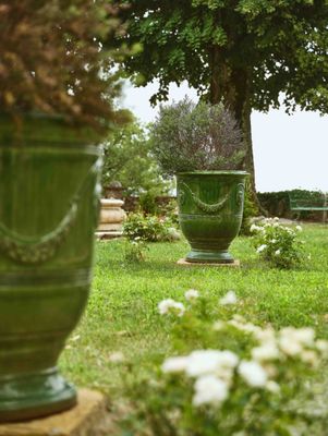 deux grands vases verts posés au milieu d'un jardin