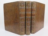 two old books sitting on top of each other on a white surface