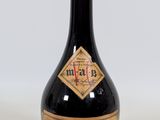 an old bottle of liquor sitting on top of a white surface