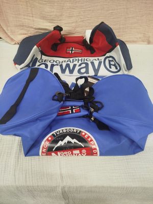 un sac bleu et rouge posé sur un lit, avec un chapeau dessus