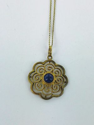 un gros plan sur un collier en or orné d'une pierre bleue au centre