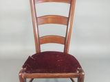 a wooden chair with a red velvet seat on it