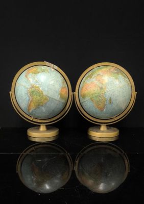 une paire de globes sur un socle posé sur une surface noire avec reflet