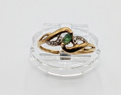 a gold ring with a green stone on top of a clear plate