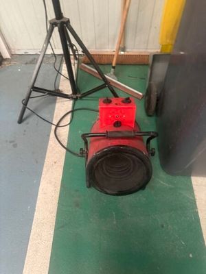 a red blower sitting on the floor next to a tripod